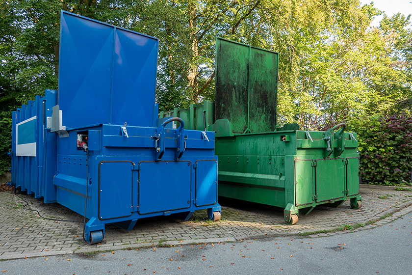 Two garbage compactors Standing next to each other on the premis